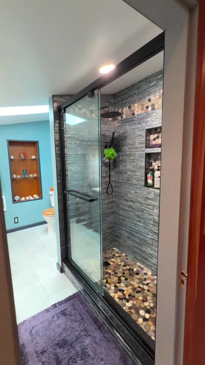 Walk-in shower with a stone tile wall and pebble floor