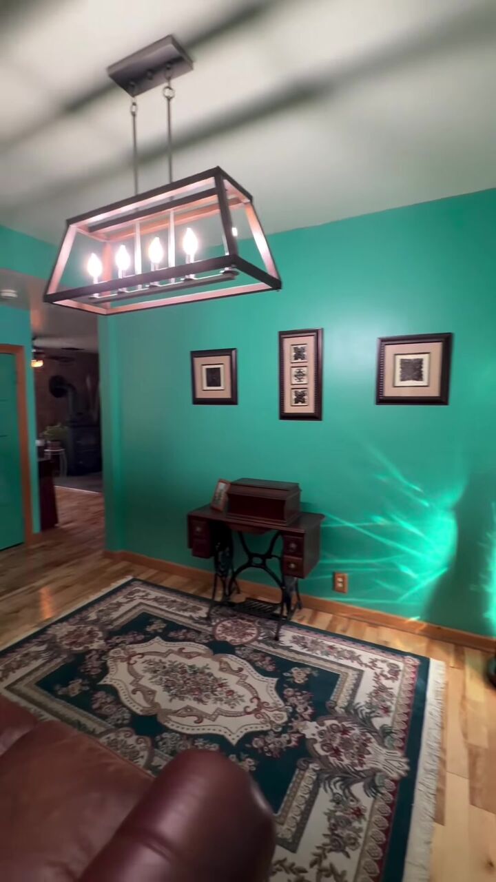 Dining room with teal walls, a hanging lantern light and an antique sewing table