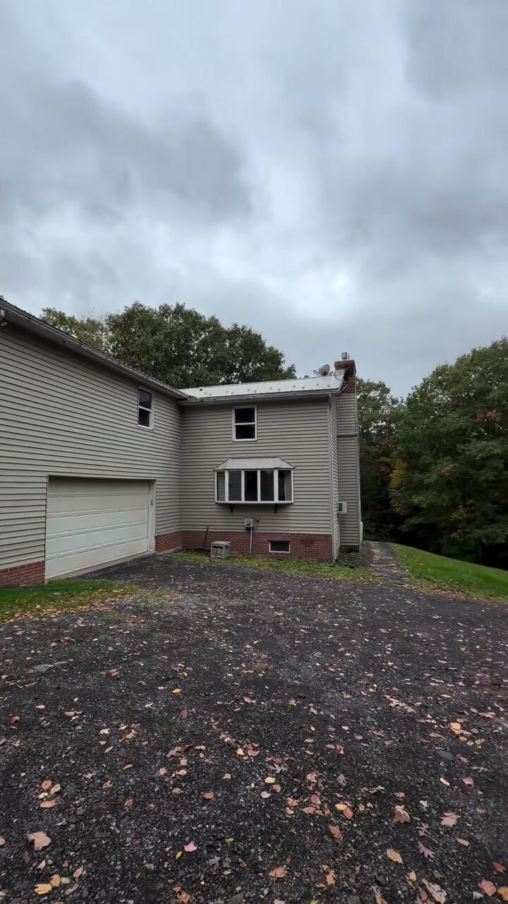 Two-story home on a big lawn under fall clouds